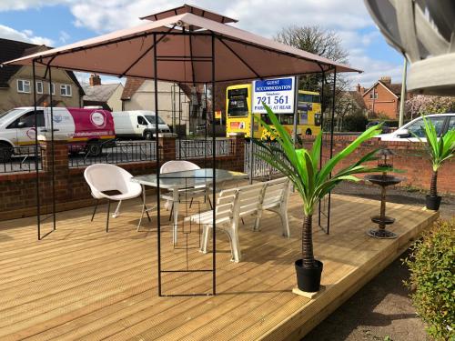 una terraza de madera con mesa y sillas bajo una sombrilla en Harris Guest Accommodation, en Oxford