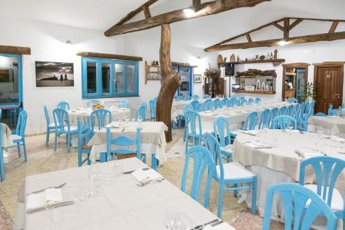une salle à manger avec des tables blanches et des chaises bleues dans l'établissement Piccolo Ranch, à Pula