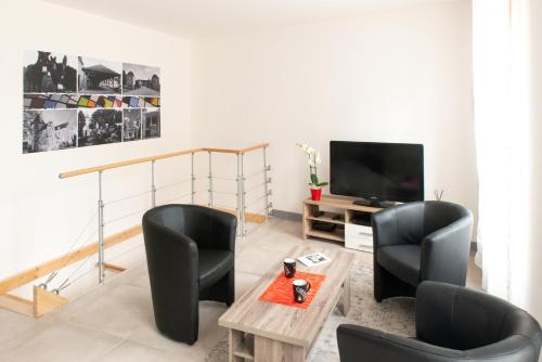 salon z 2 krzesłami i telewizorem w obiekcie Appartement Duplex Totalement Meuble Et Equipe w mieście Lignières