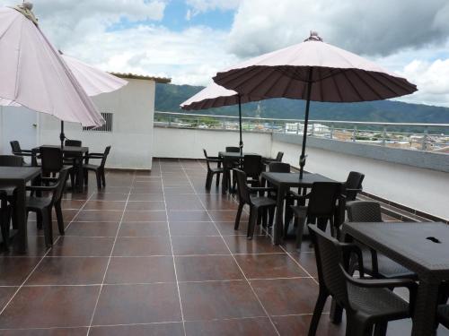 a patio with tables and chairs and umbrellas on a roof at HOTEL ESCORIAL PITALITO in Pitalito
