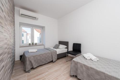 une chambre avec deux lits et une chaise et une fenêtre dans l'établissement Balen city central house for 8, à Novalja