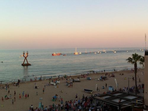 a crowd of people on a beach with boats in the water at Cal Xillo in Torredembarra
