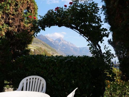 une chaise blanche assise sous une arche avec des roses dans l'établissement Big flat in the heart of Valais, à Martigny-Combe