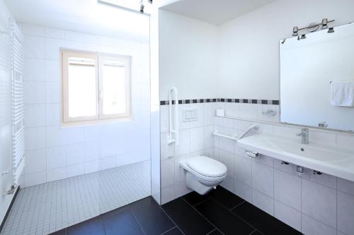 a white bathroom with a toilet and a sink at Hotel TURNA Malbun in Malbun
