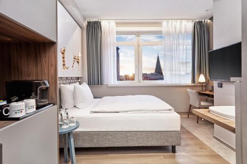 a hotel room with a bed and a window at H+ Hotel Bremen in Bremen