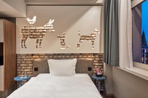 a bedroom with a bed and some animals on the wall at H+ Hotel Bremen in Bremen