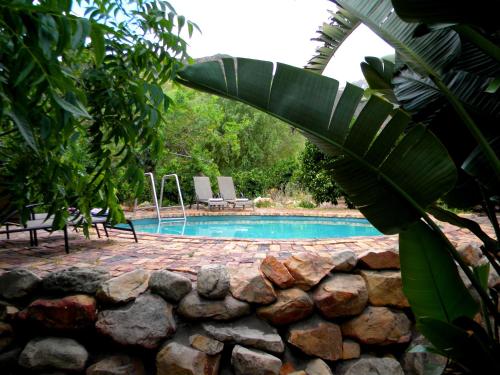 a swimming pool with a stone wall next to afficiency at Klein Boschkloof Chalets in Clanwilliam