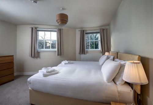 a bedroom with a large white bed with two windows at The Royal Foundation of St Katharine in London