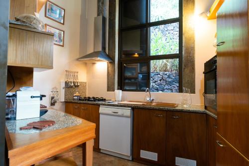 una cucina con armadi in legno, lavandino e finestra di Caloura 66 a Lagoa
