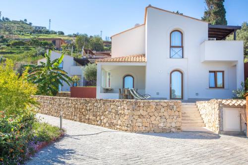 a white house with a stone wall at Cefalù In Casa in Cefalù