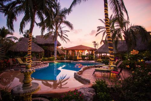 a swimming pool with palm trees and a resort at Present Moment Retreat in Troncones