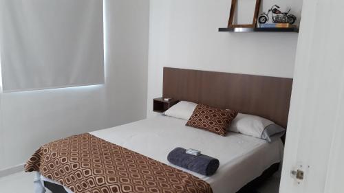 1 dormitorio con 1 cama con manta y almohadas marrones en CH1 Bonito apartamento amoblado en condominio RNT 1O8239 en Valledupar