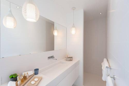 a white bathroom with a sink and a mirror at Villa King Gustaf in Gustavia