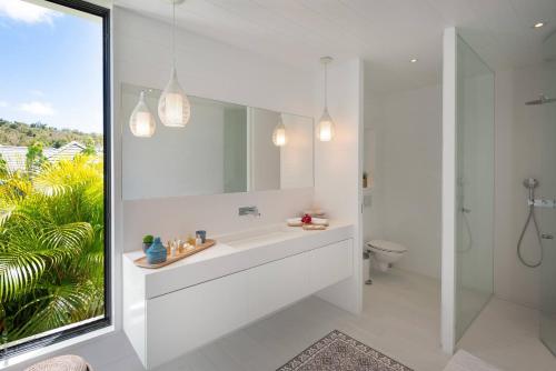 a white bathroom with a sink and a mirror at Villa King Gustaf in Gustavia
