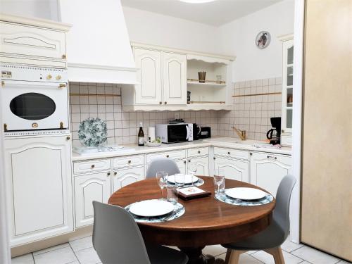 エクスレバンにあるAu Julliardの白いキャビネット、木製テーブルと椅子付きのキッチンが備わります。