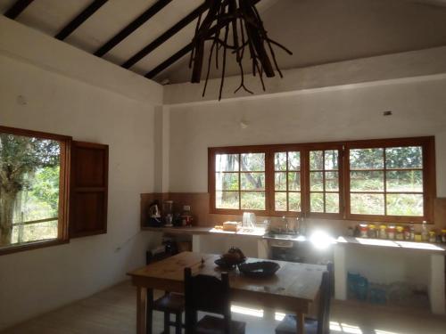 a kitchen with a table and a dining room with windows at Casa de Teja Barichara in Barichara
