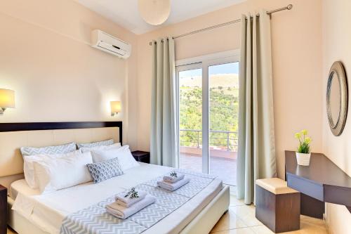 a bedroom with a large bed and a balcony at Oceana Suites in Georgioupolis