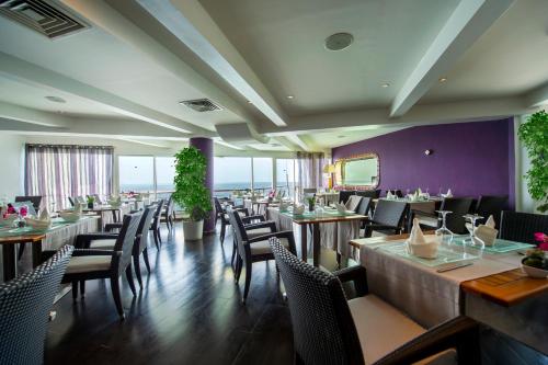 un restaurant avec des tables et des chaises en bois et des murs violets dans l'établissement Hotel Lagon 2, à Dakar