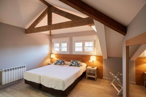 a bedroom with a bed and two windows at Hotel Ribadesella Playa in Ribadesella