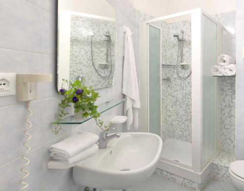 a white bathroom with a sink and a shower at Little Hotel in Riccione