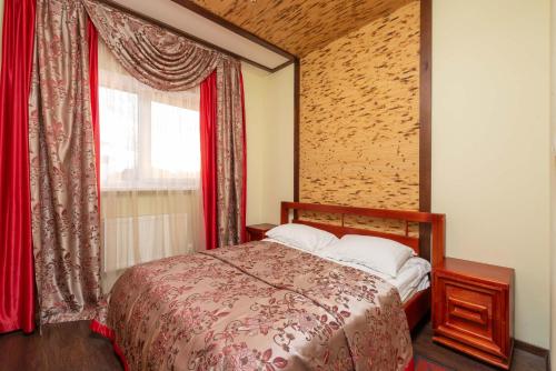 a bedroom with a bed with red curtains and a window at Brech Resort&Spa in Gurinovka Staraya