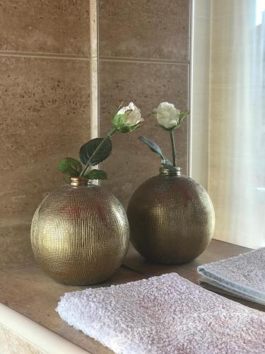 two bronze vases with flowers in them on a counter at Dosud House Studios in Split