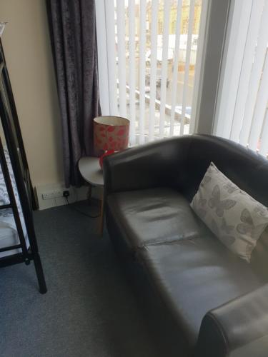 a black leather couch in a living room with a window at Langroyd Hotel in Blackpool
