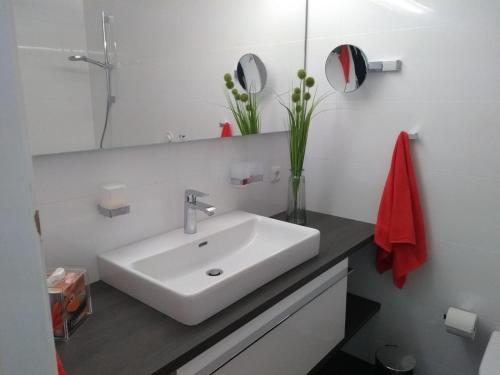 Un baño blanco con lavabo y espejo. en Ferienwohnung-Apartment-Seeblick-in-Plaza-Marit-Residenz, en Timmendorfer Strand