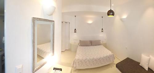 a white bedroom with a bed and a mirror at Tataki Hotel in Fira