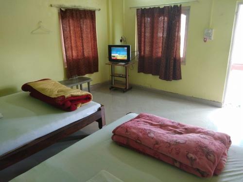 a bedroom with two beds and a tv in it at Gorumara Nature's Cottage (A Unit Of M/S Ecological & Tours) in Jalpāiguri