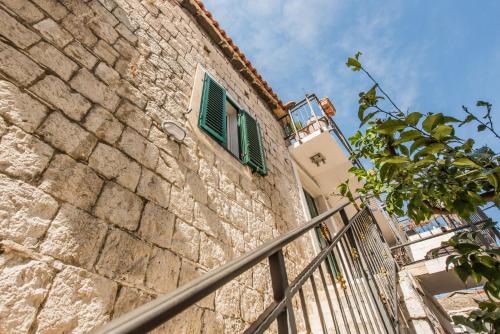 a stone building with a green window and a fence at Kovacic Rooms in Split