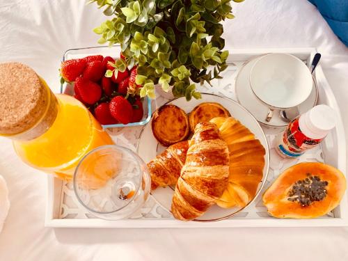 a tray of food with pastries and fruit on a bed at Apartments Alfacinha Ajuda in Lisbon
