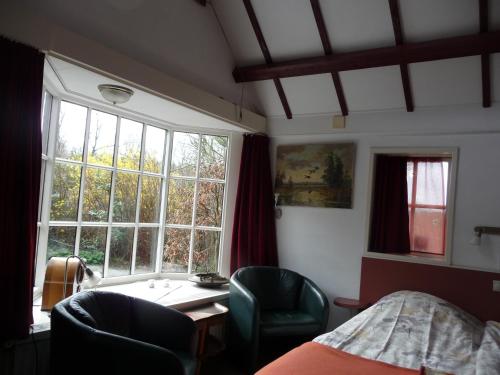 a bedroom with a bed and a desk and a window at Selatuinen in Appelscha