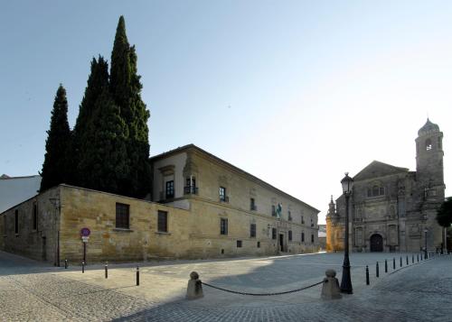 a large stone building with a clock tower on a street at Parador de Ubeda in Úbeda