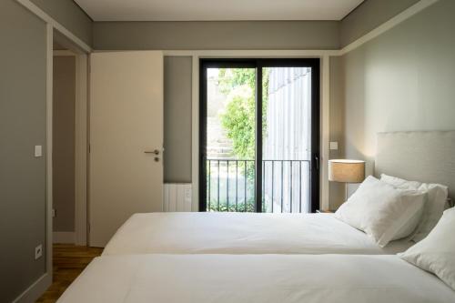 a bedroom with a large white bed and a window at Porto Republica Apartments in Porto