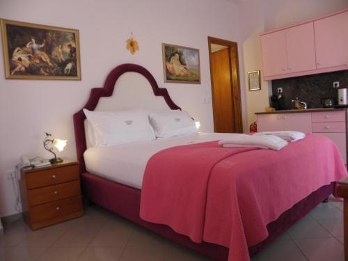 a bedroom with a large bed with a pink blanket on it at Irida Beach Resort Suites in Kyparissia