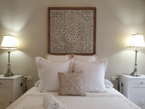 1 dormitorio con 1 cama con almohadas blancas y 2 lámparas en Apartamento La Judería de San Clemente, en Sevilla