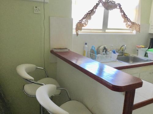 a kitchen with two chairs and a counter with a sink at Hastings Central 3D Studio Apt Opp Beach in Bridgetown