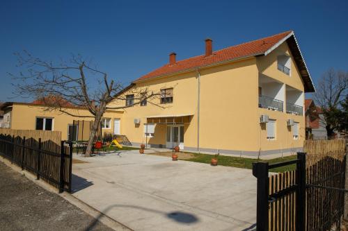 a large yellow house with a fence in front of it at Apartments Kuca Aleksic in Niš