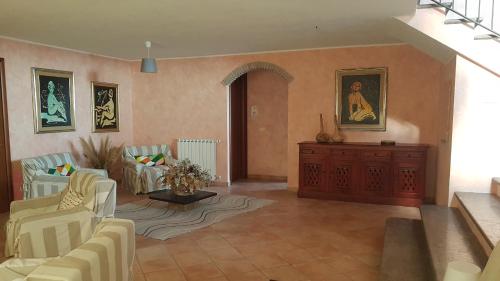 a living room with white chairs and a dresser at Villa Isotta in Trevignano Romano