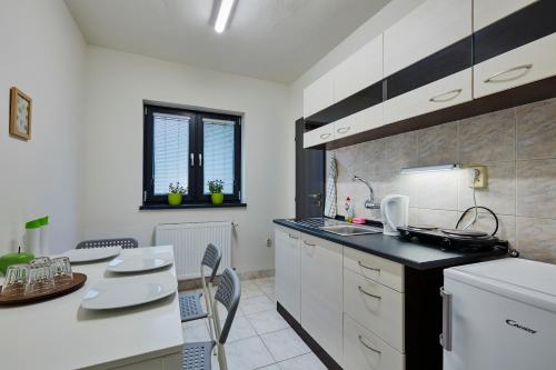 科希策Holiday houses BARCA的配有白色橱柜、桌子和椅子的厨房