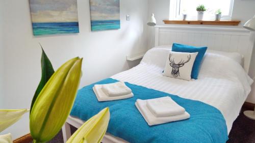 a bedroom with a bed with towels and a plant at Flat 14d Bayhead in Stornoway