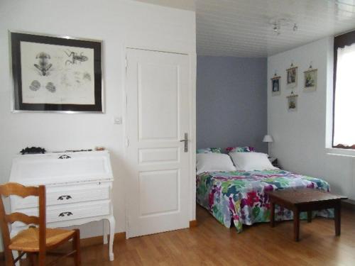 ein Schlafzimmer mit einem Bett, einer Kommode und einem Tisch in der Unterkunft Chambres d'hôtes La Luce in Démuin