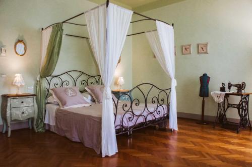 ルッカにあるVilla Agnese Suitesのベッドルーム1室(ピンクの枕が付いた天蓋付きベッド1台付)