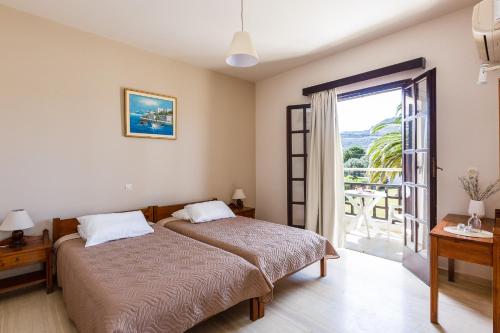 sypialnia z 2 łóżkami i przesuwnymi szklanymi drzwiami w obiekcie Santa Maria Studios & Apartments w mieście Plakias