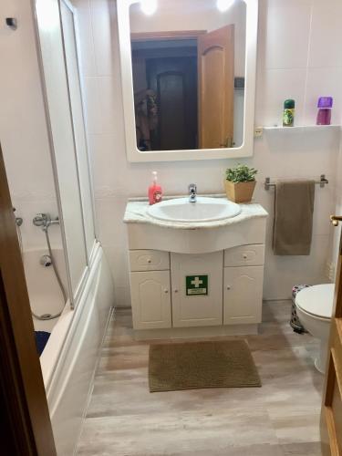 a white bathroom with a sink and a mirror at Ericeira Ocean View Apartment in Ericeira