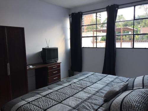 Schlafzimmer mit einem Bett, einem TV und Fenstern in der Unterkunft Casa 10 Guest house in Guatemala