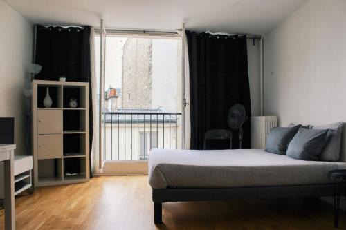 une chambre avec un lit et une grande fenêtre dans l'établissement Lauriston Nice Studio, à Paris