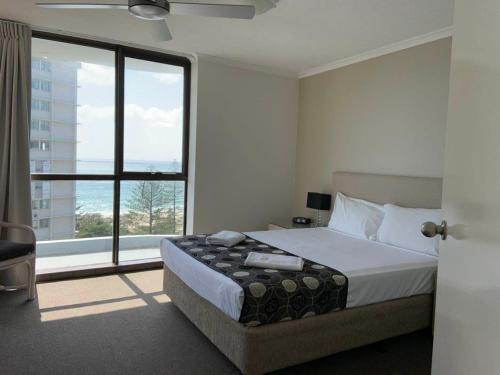 a bedroom with a bed and a large window at Burleigh Gardens North Hi-Rise Holiday Apartments in Gold Coast