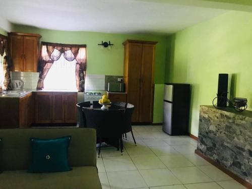 eine Küche mit grünen Wänden und einem Tisch im Zimmer in der Unterkunft Bougainvillea Apartments 2 in Castries